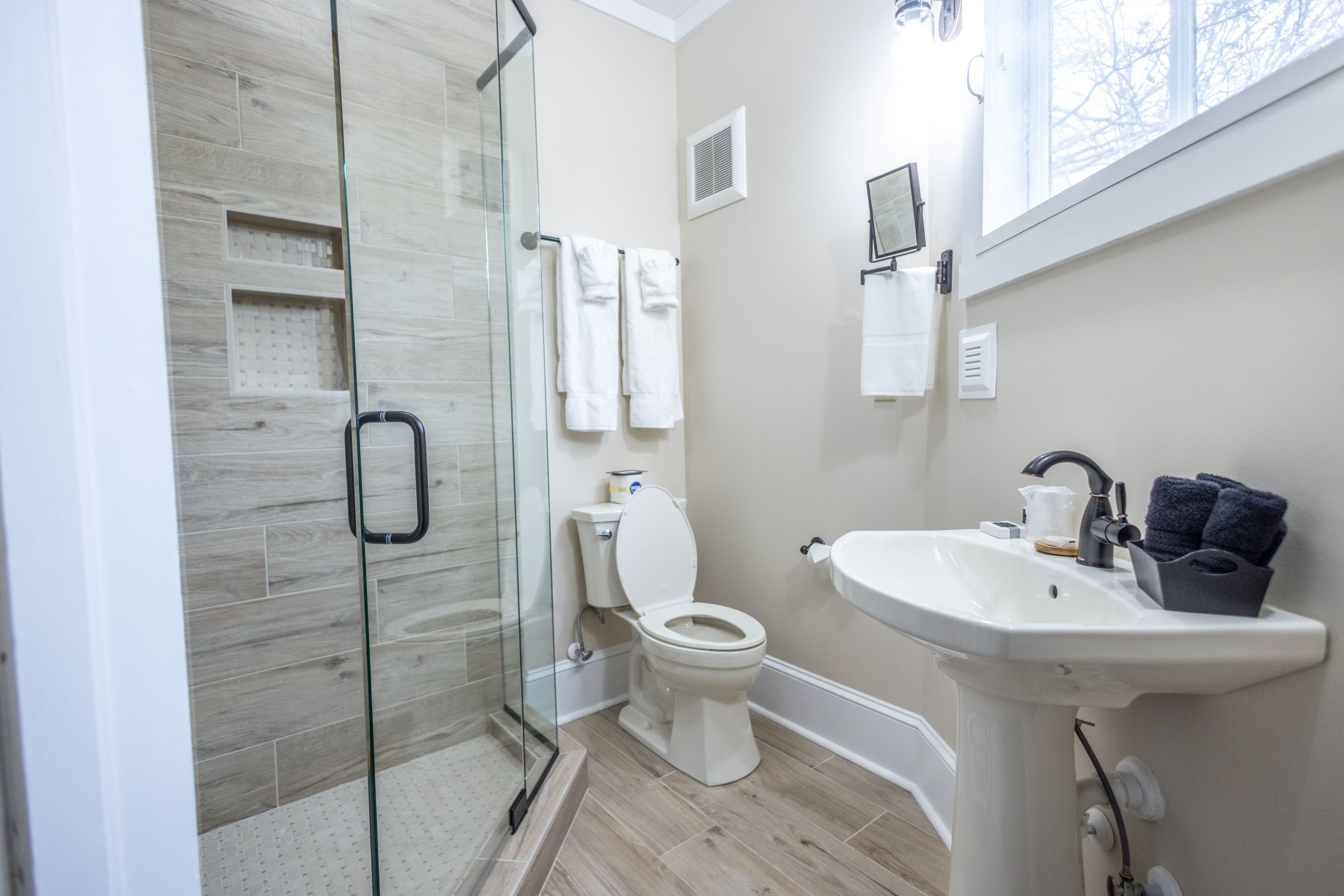 Bathroom features a large, corner, tiled walk-in shower, toilet, and stand-alone sink.