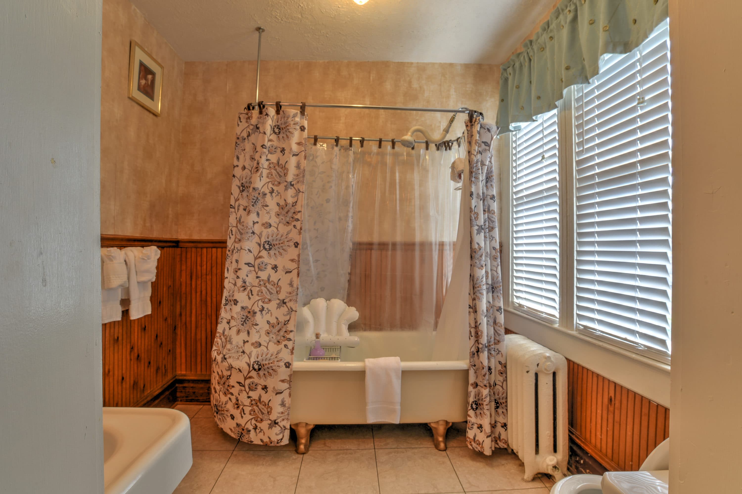 Bathroom features a claw-foot tub with wrap around shower curtain.