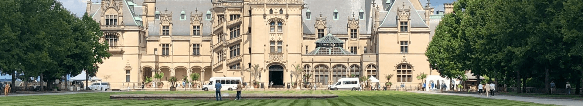 A historic mansion with a landscaped lawn and visitors enjoying the grounds.