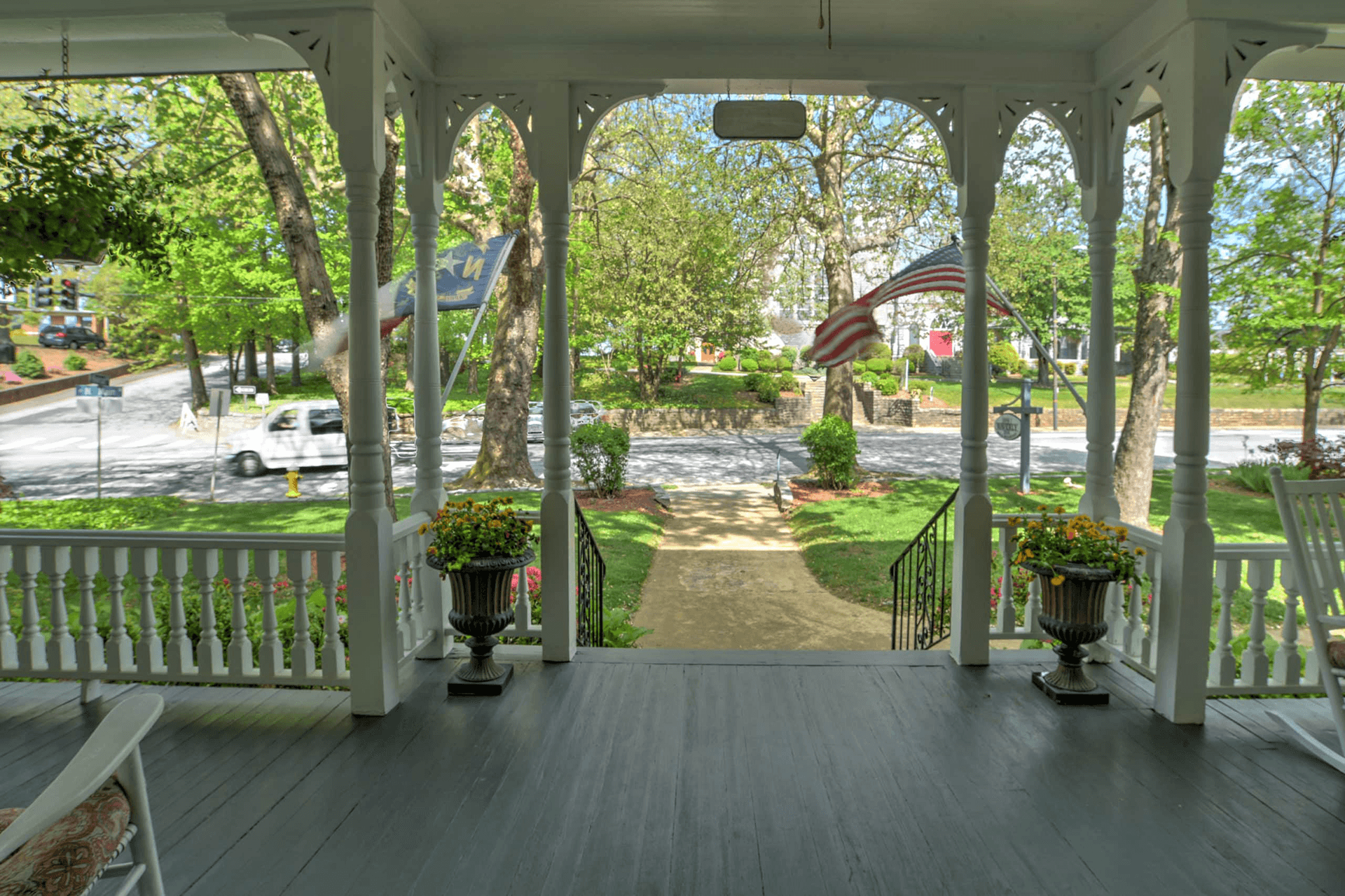 View from a porch overlooking a tree-lined street with an American flag gently waving.