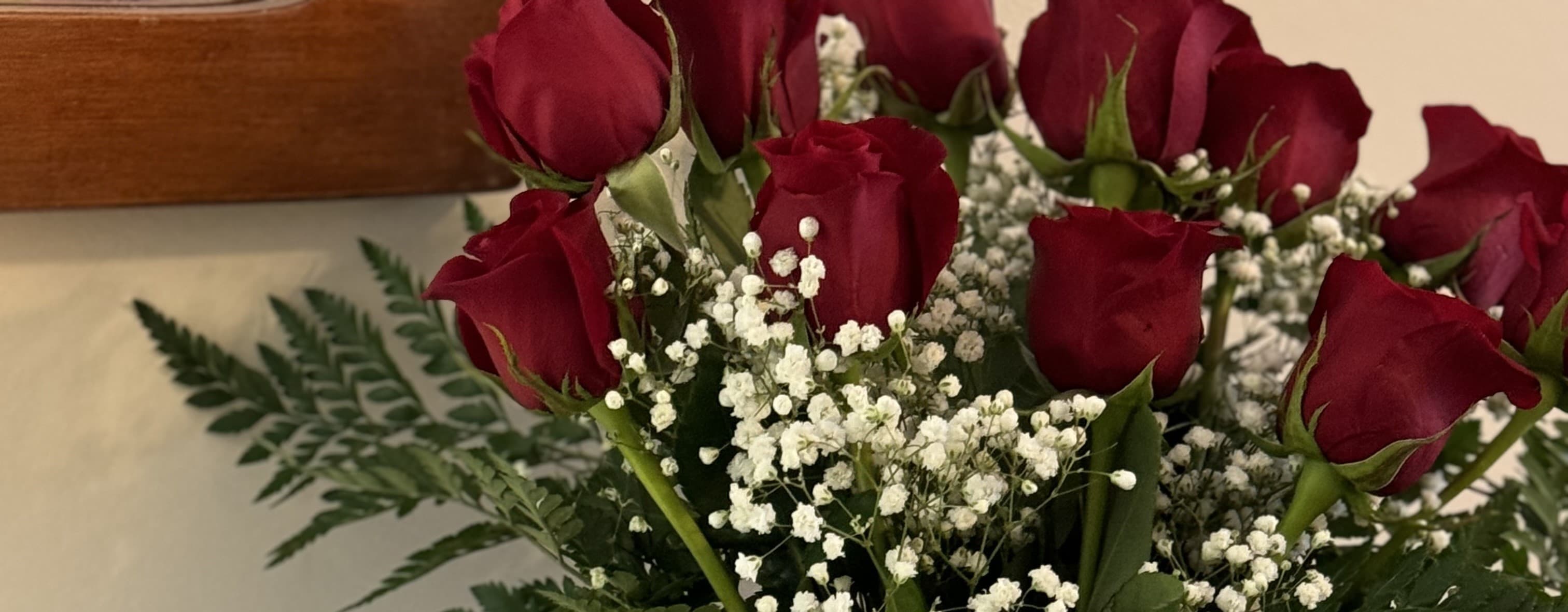 A bouquet of red roses surrounded by baby's breath and greenery.